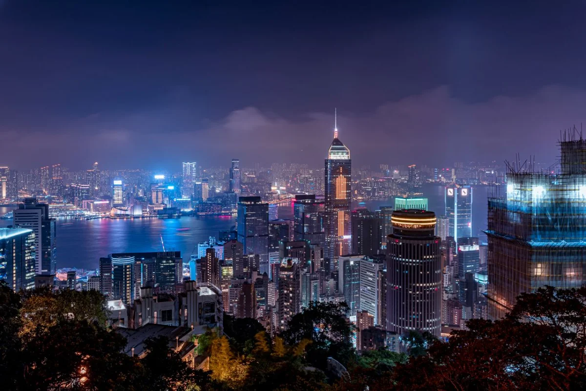 Night photograph of the Hong Kong skyline and Victoria Harbour seen from the hills above the city